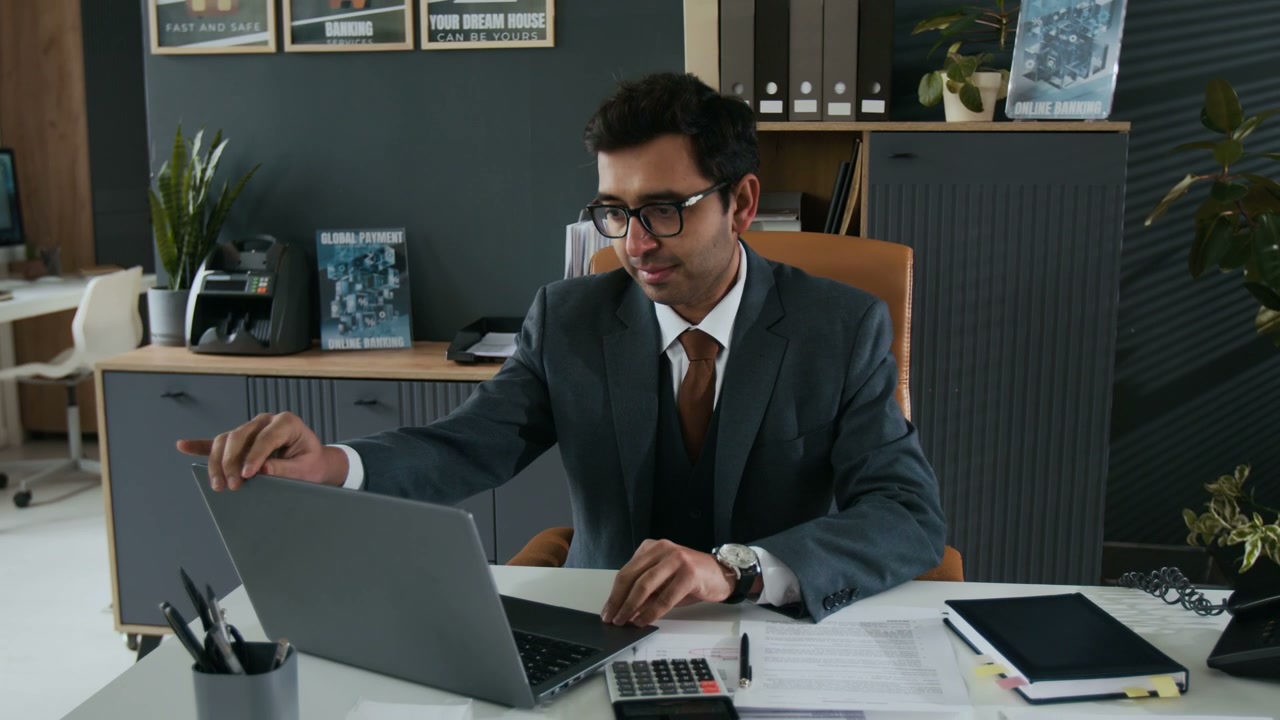Professional Man at Office Desk Looks at Camera
