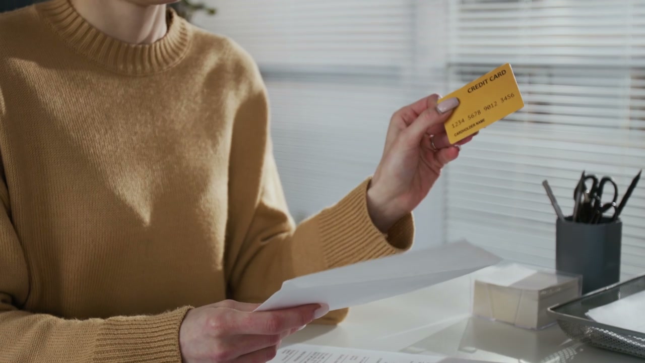 Person Holding Credit Card and Document in Office
