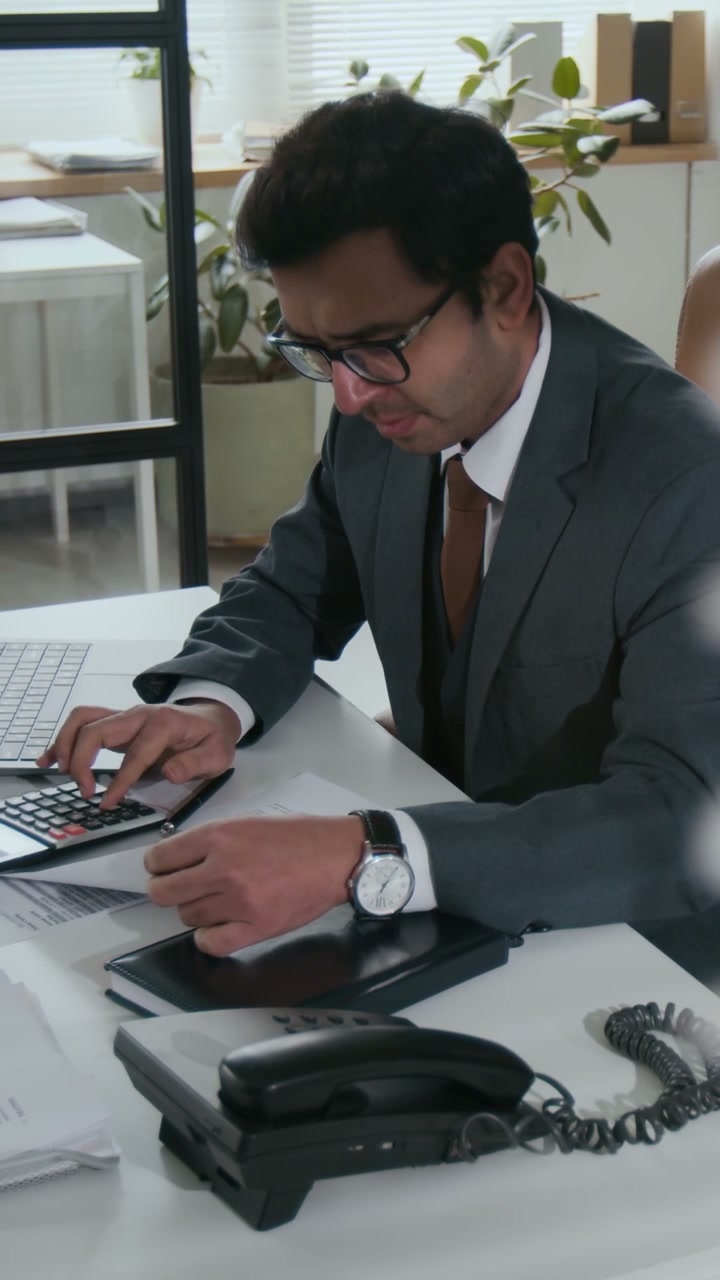 Businessman Calculating Finances at Office Desk