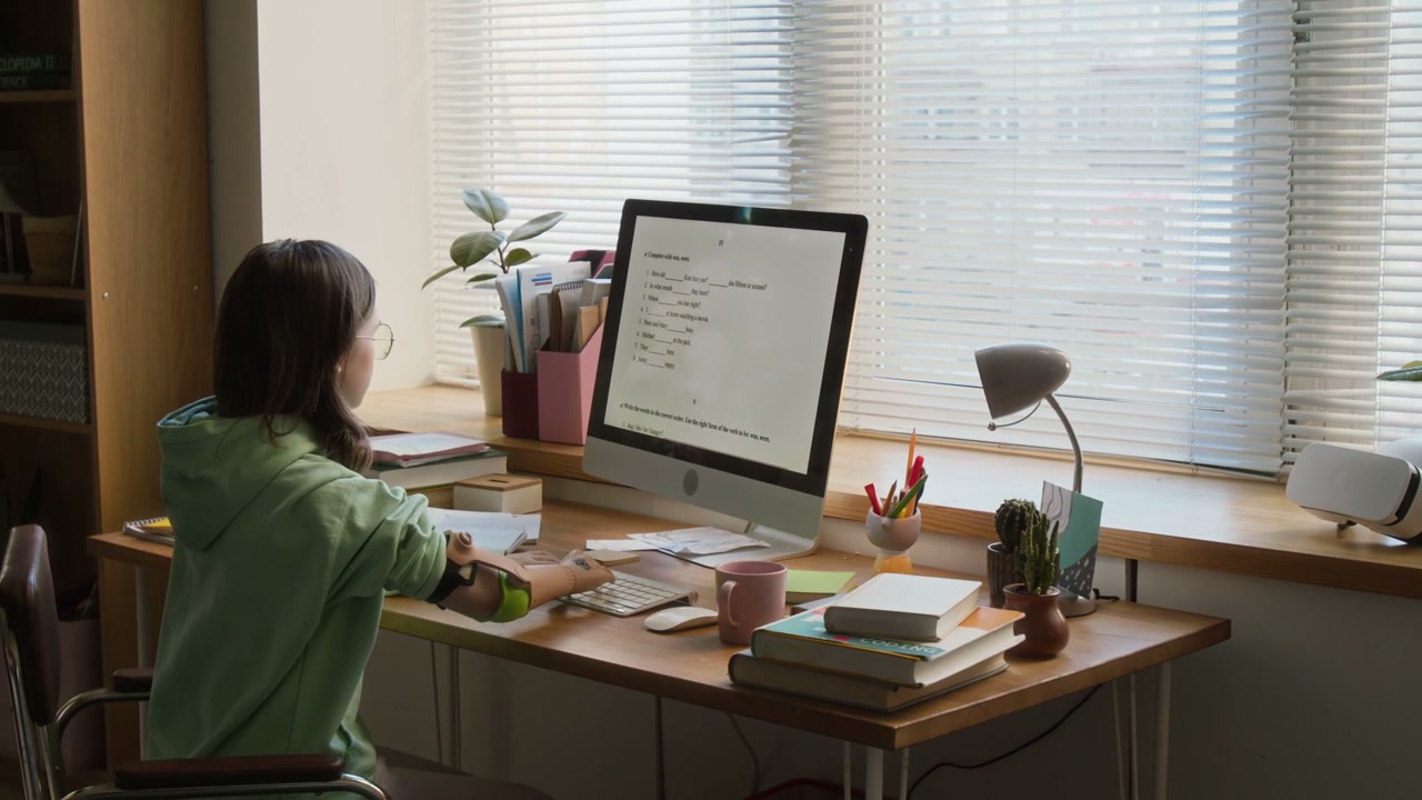 Young Woman with Prosthetic Arm Studies at Desk