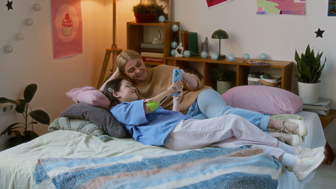 Mother and Daughter Scrolling Phone on Bed