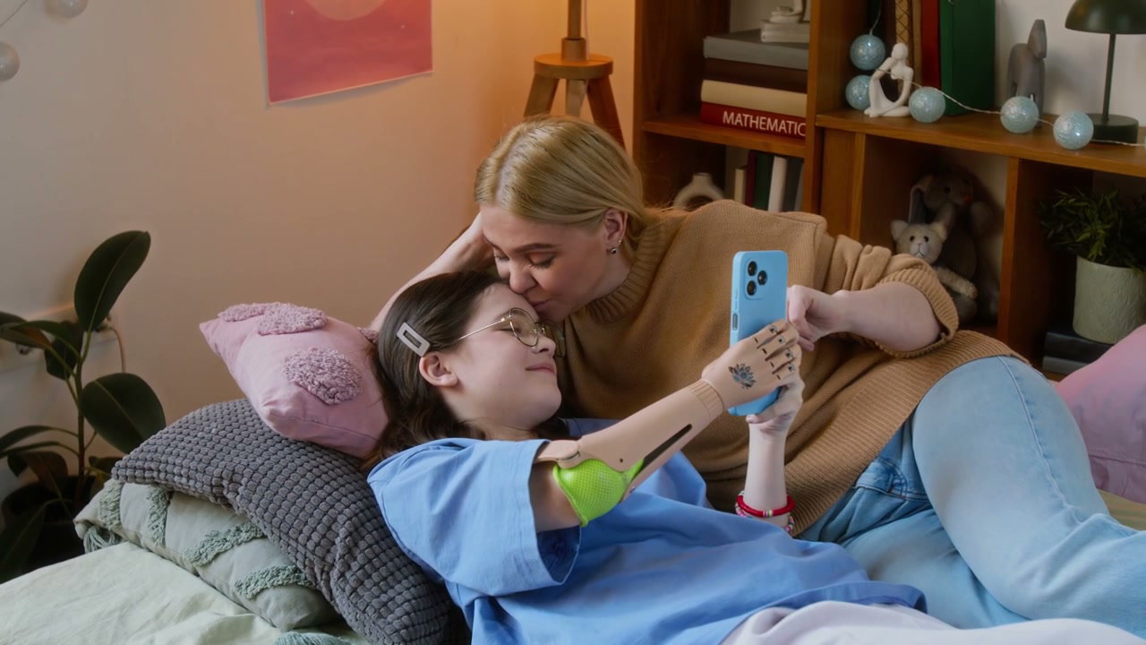 Mother and Daughter Using Smartphone on Bed
