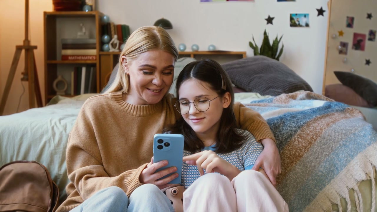 Mother and Daughter Using Smartphone in Bedroom