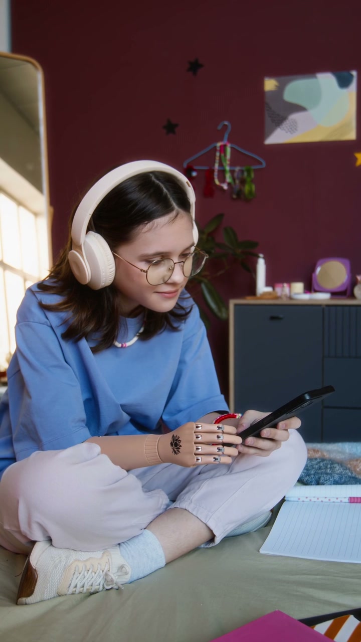 Girl with Prosthetic Arm Using Phone on Bed