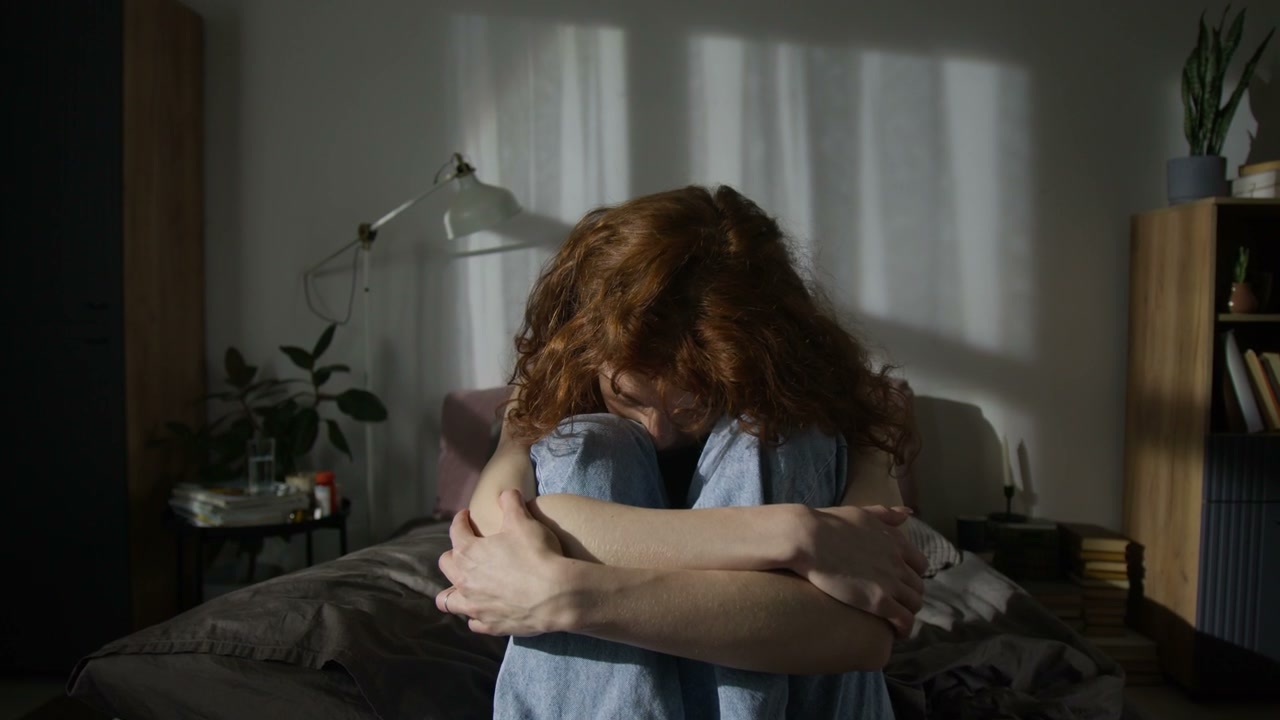 Melancholy Woman on Bed Looks at Camera