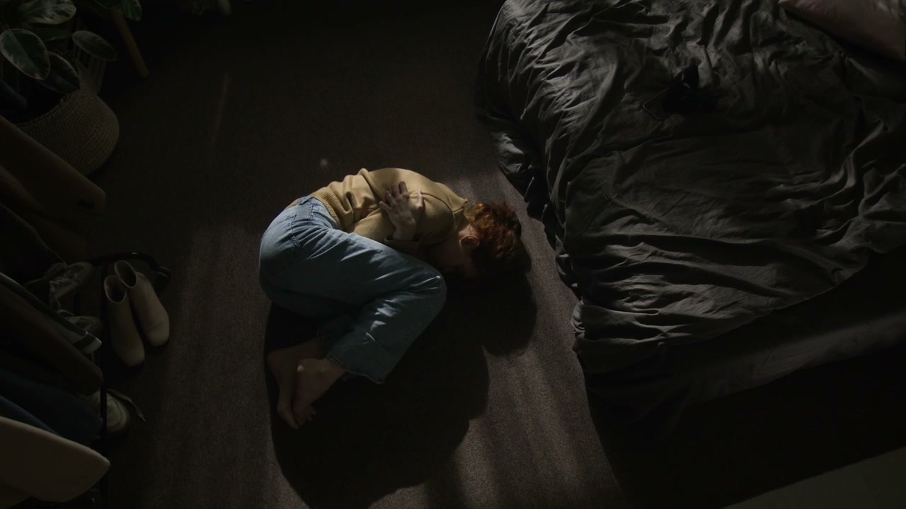 Sad Woman Curled Up on Bedroom Floor