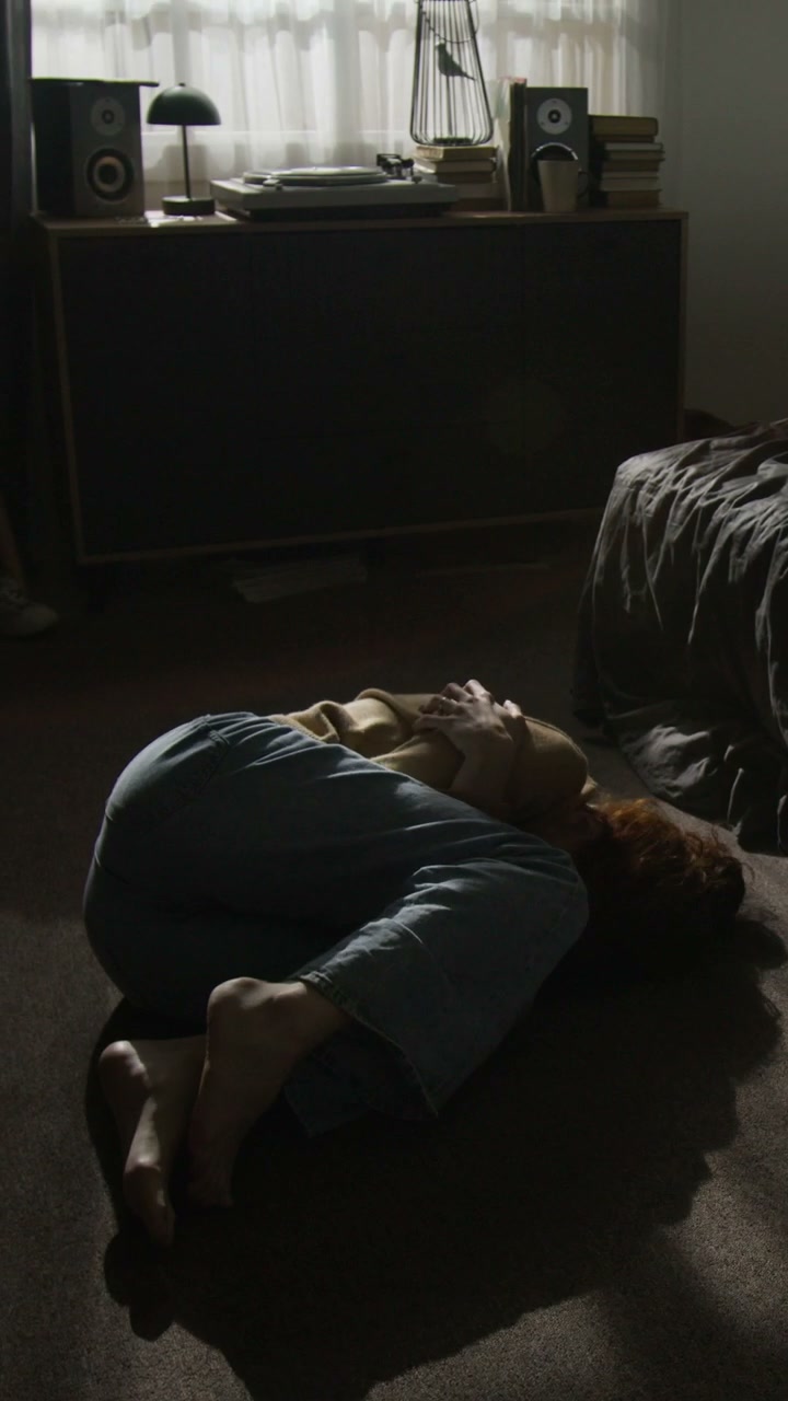 Depressed Woman Lying on Bedroom Floor
