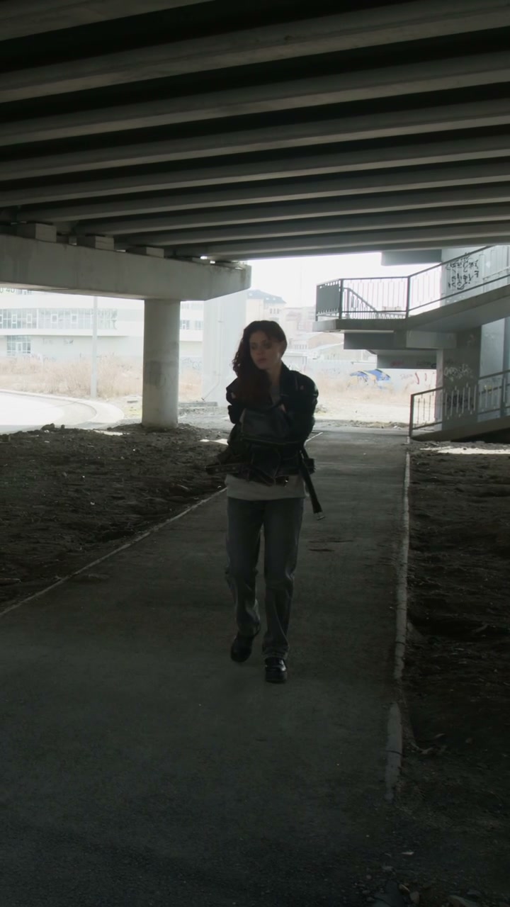 Melancholy Woman Walks Under Concrete Bridge