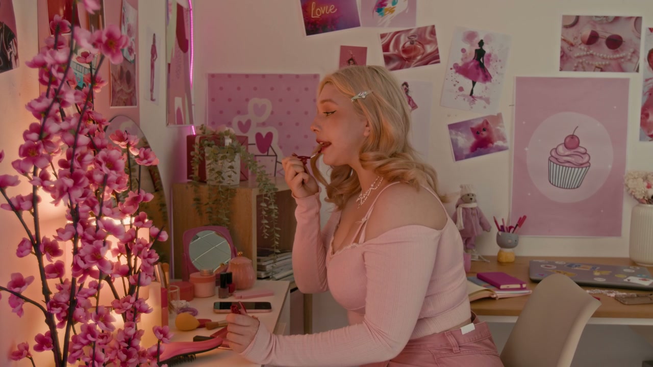 Blonde Woman Applying Lipstick in Pink Room
