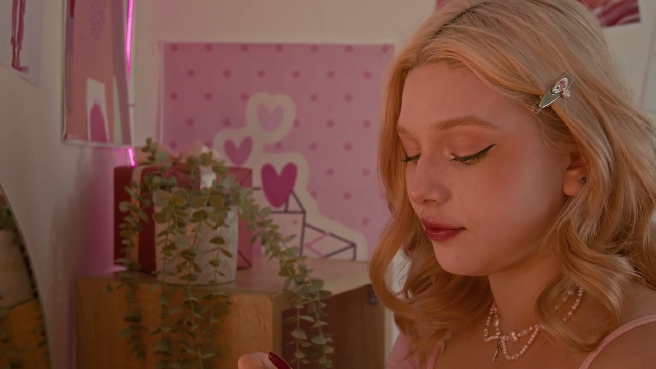 Young Woman Applying Lipstick in Pink Room