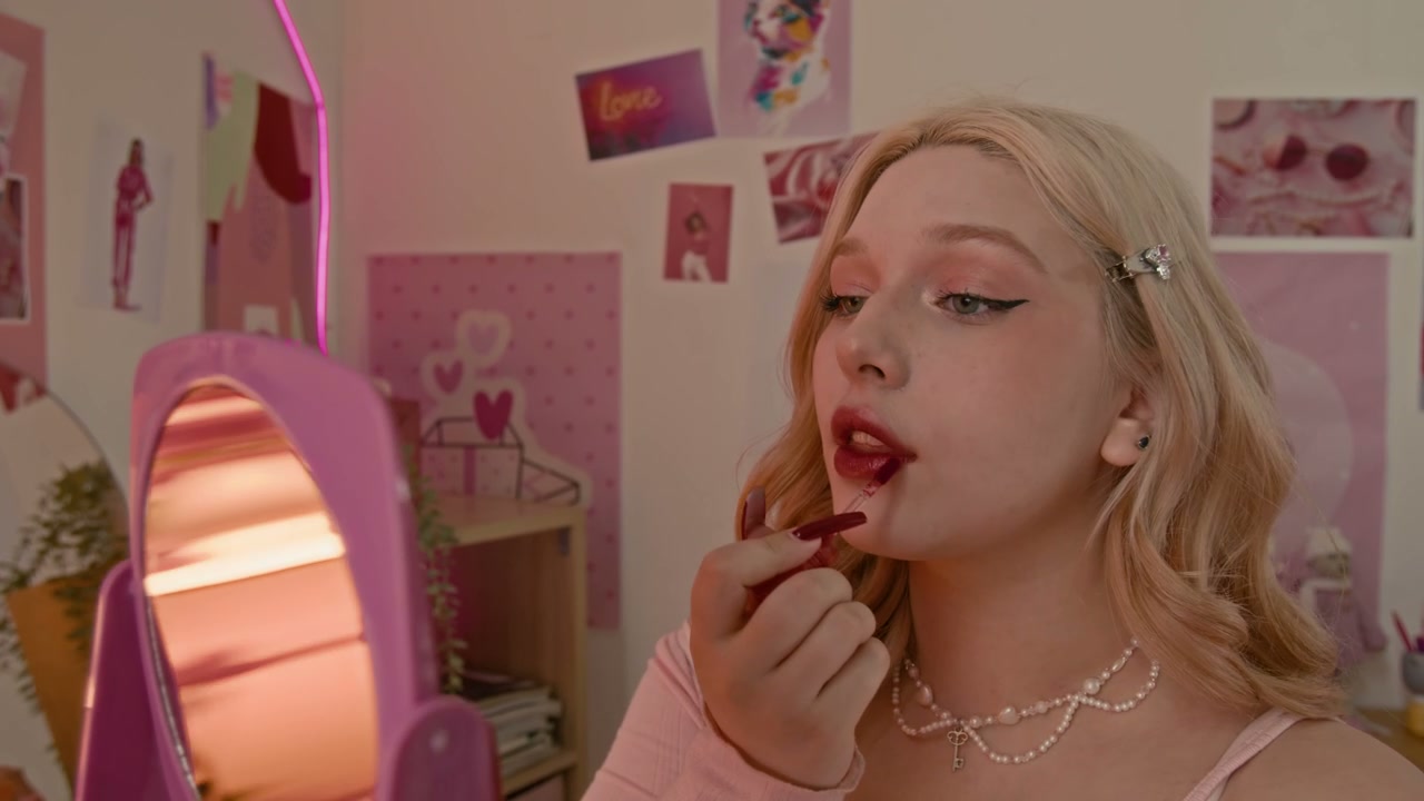 Young Woman Applying Lipstick in Pink Room
