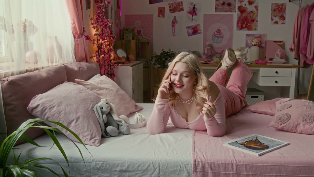 Happy Young Woman Talking on Phone in Pink Bedroom