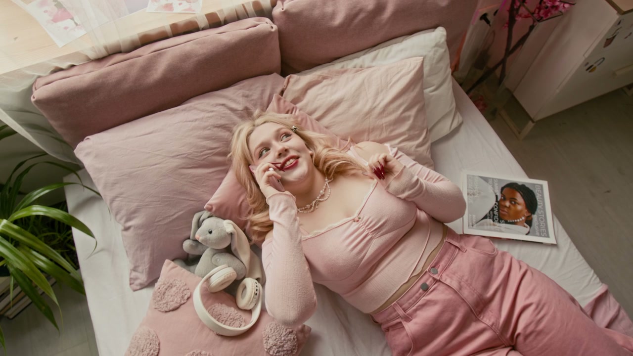 Young Woman Talking on Phone in Pink Bedroom