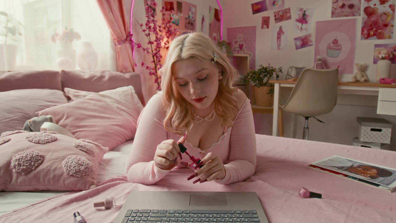 Young Woman Painting Nails in Pink Bedroom