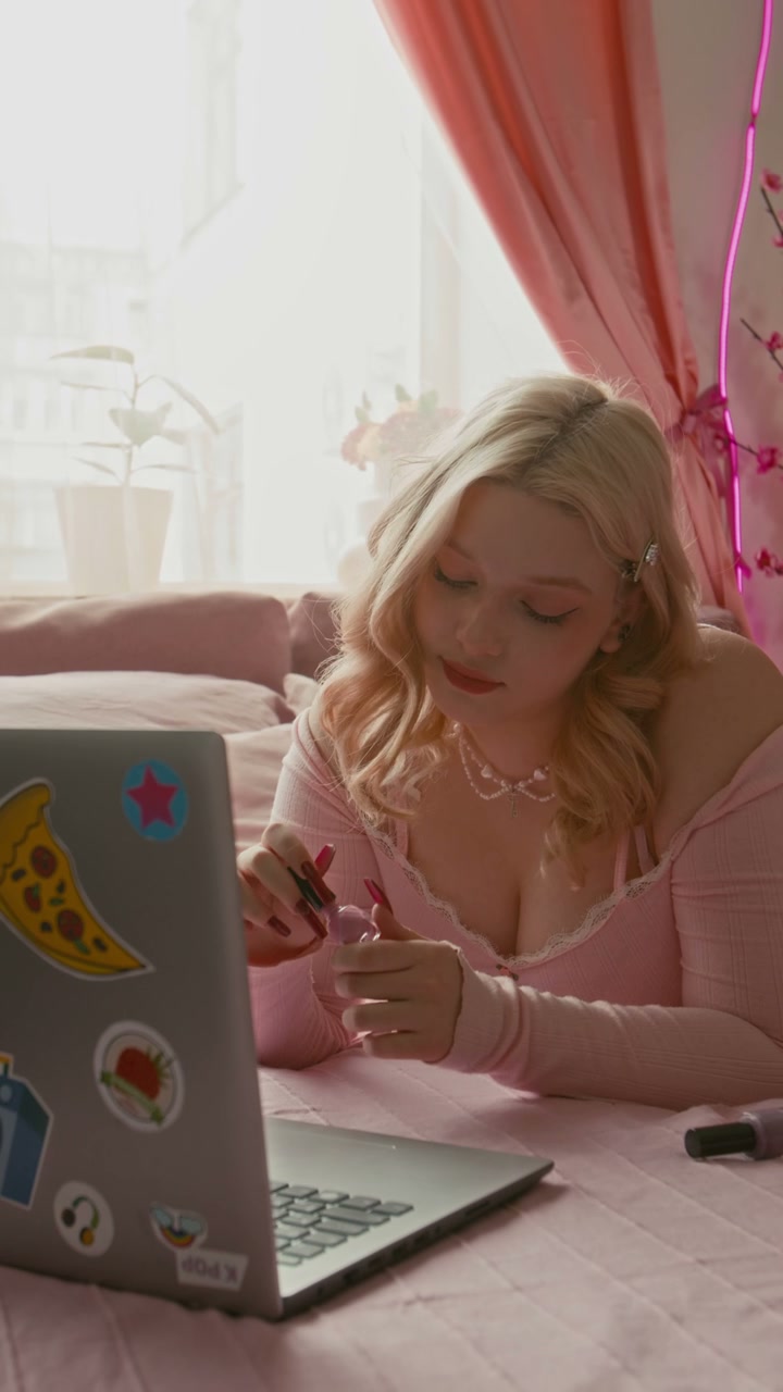 Blonde Woman Applying Nail Polish on Pink Bed