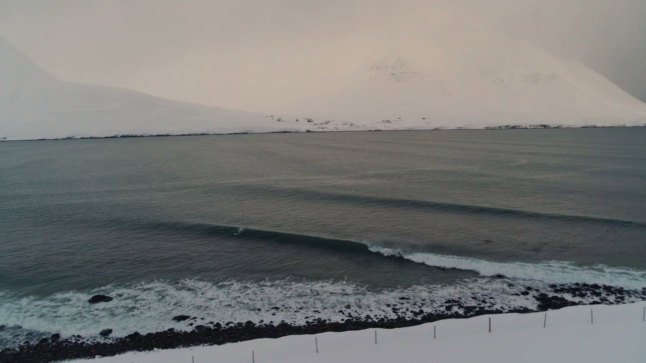 Winter Surfing Along Snowy Coastline
