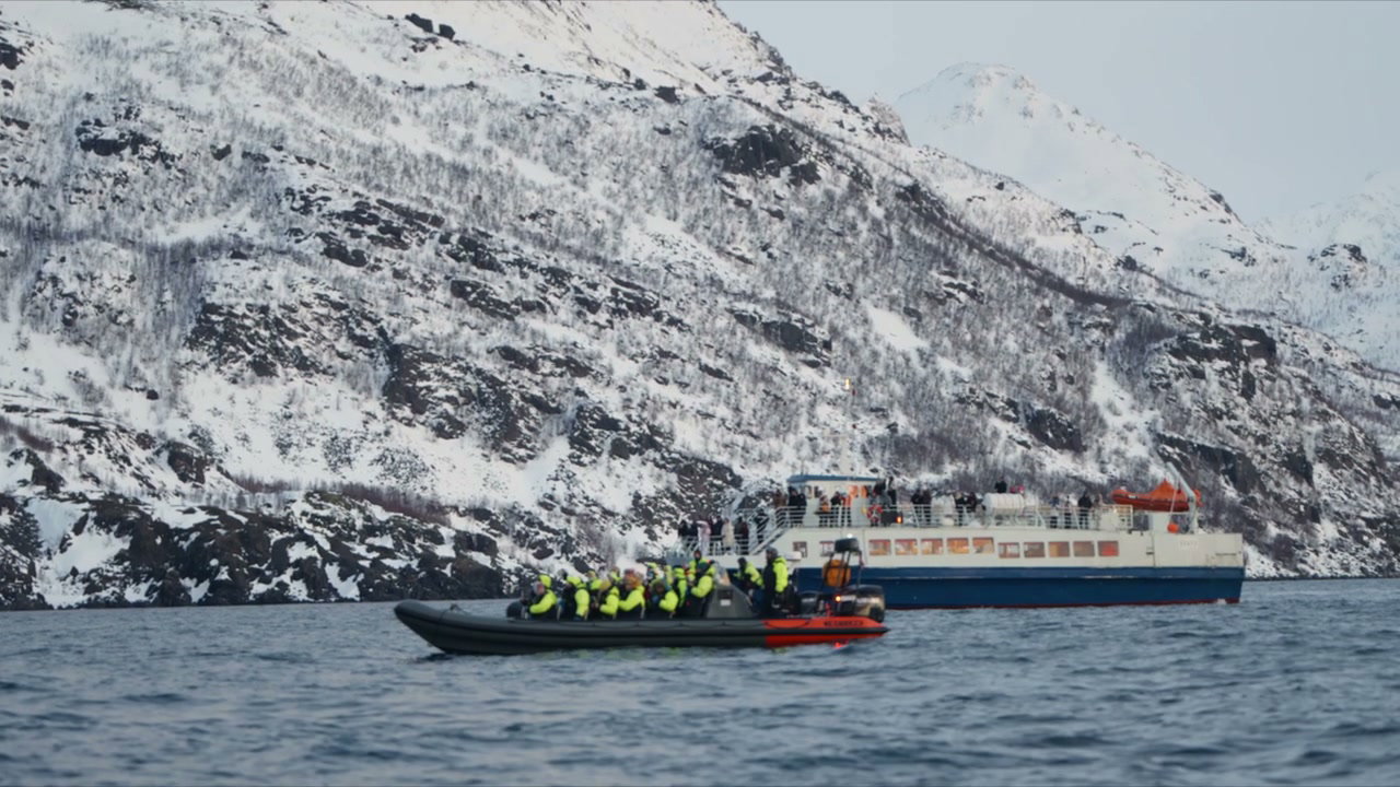 Tourists in Boat Against Snowy Fjord Mountains