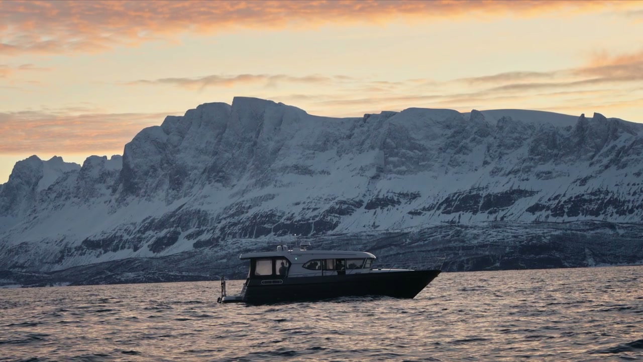 Boat on Arctic Fjord with Snow Mountains at Sunset