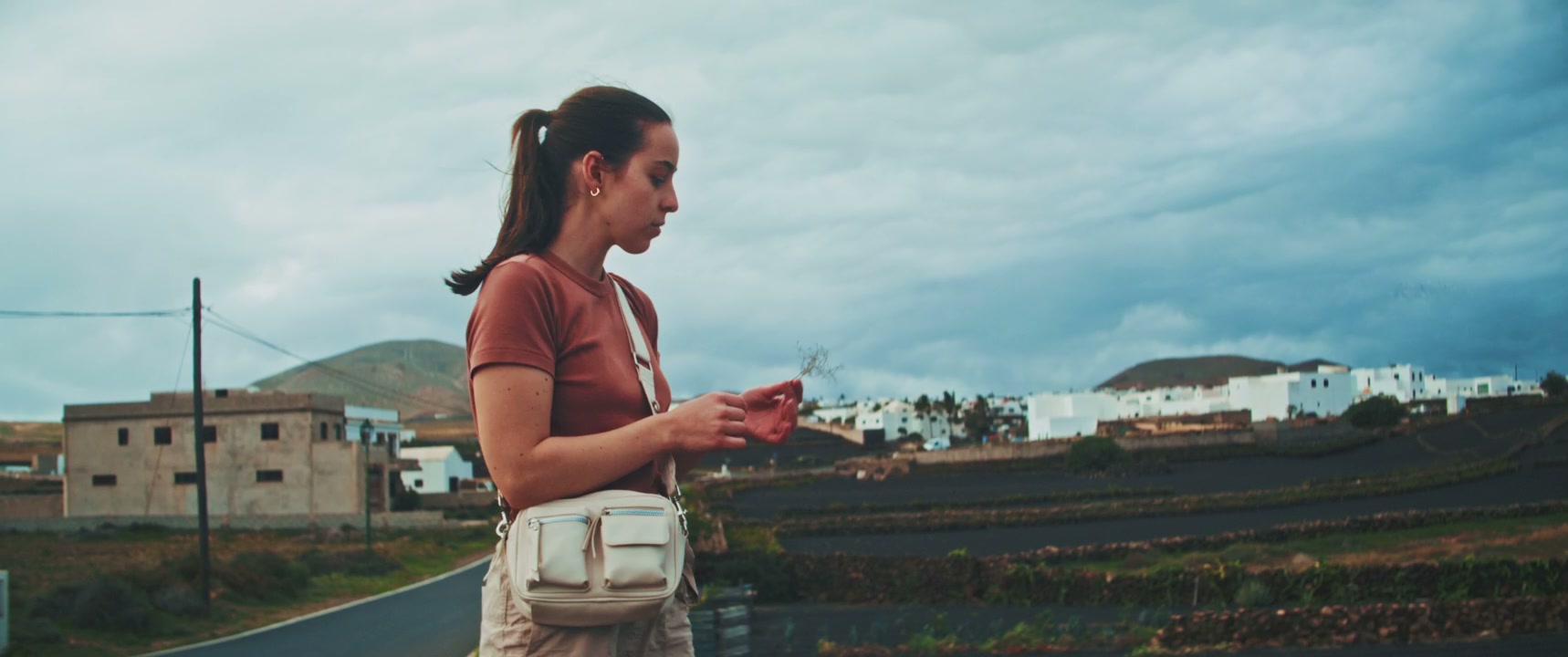 Woman Examining Plant in Volcanic Landscape