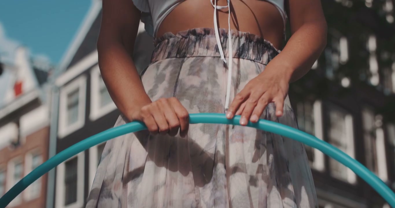 Woman Holding Hula Hoop Smiling on City Street