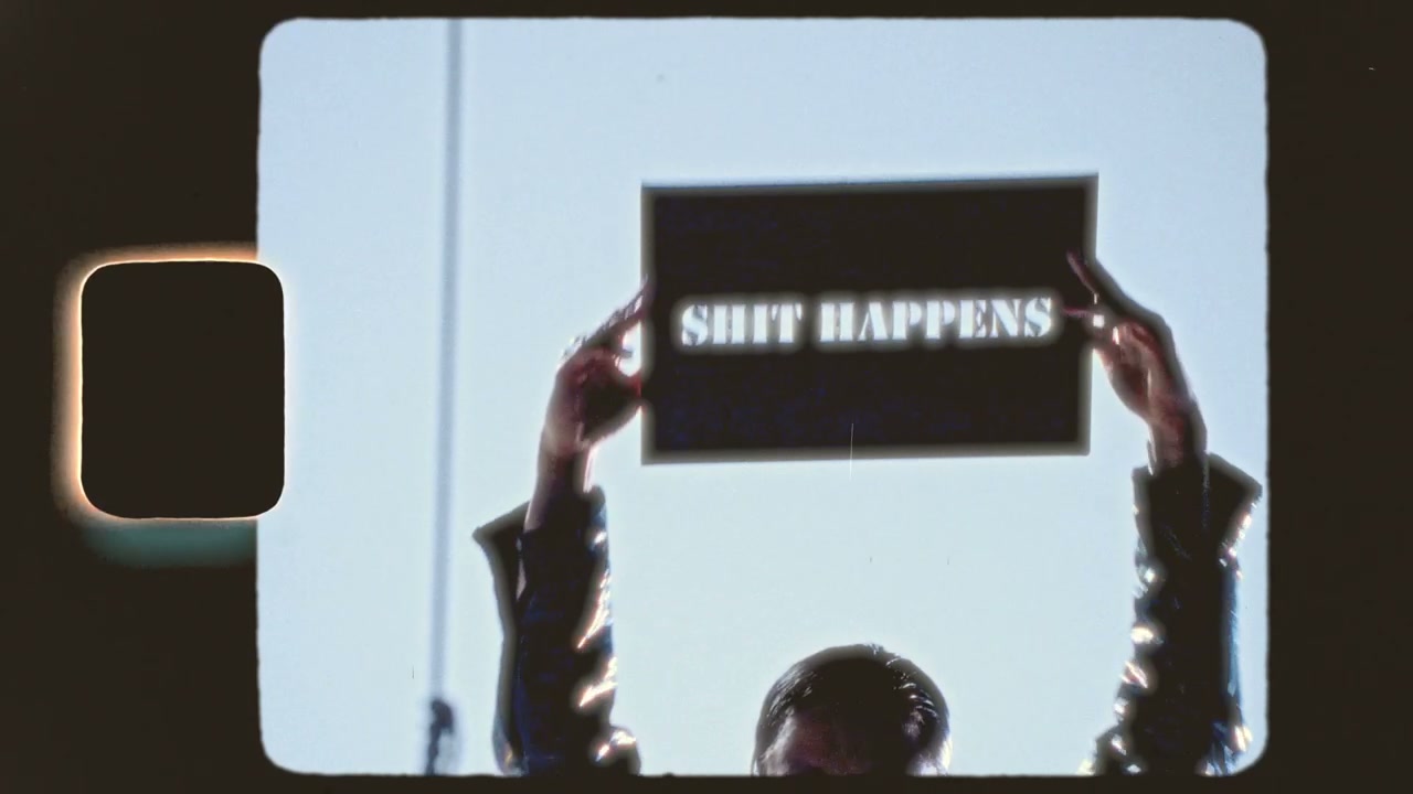Avant-Garde Performer Holding 'Shit Happens' Sign