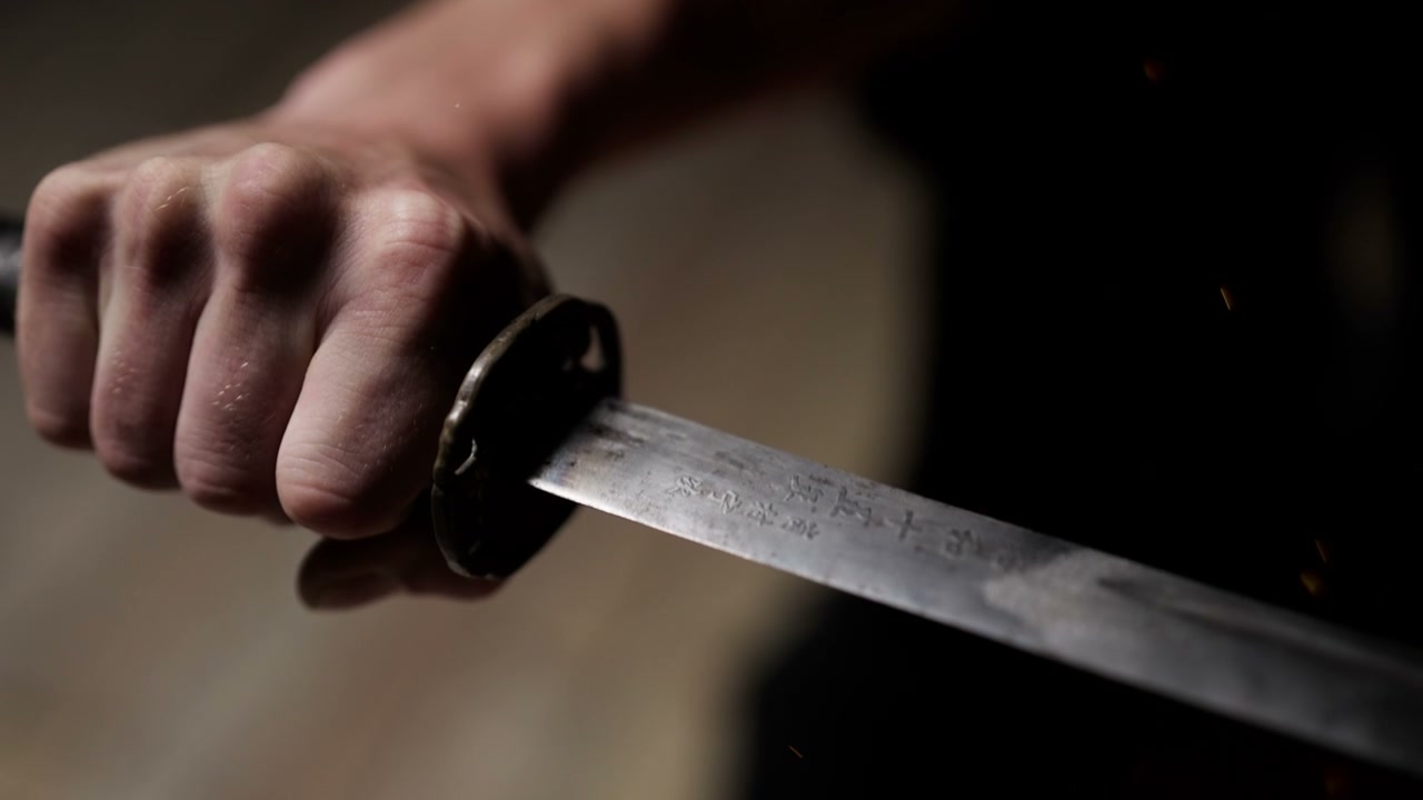 Close-up of Hand Gripping Katana Blade With Sparks