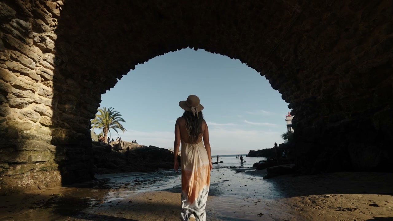 Woman Walking Under Stone Arch on Portugal Coast