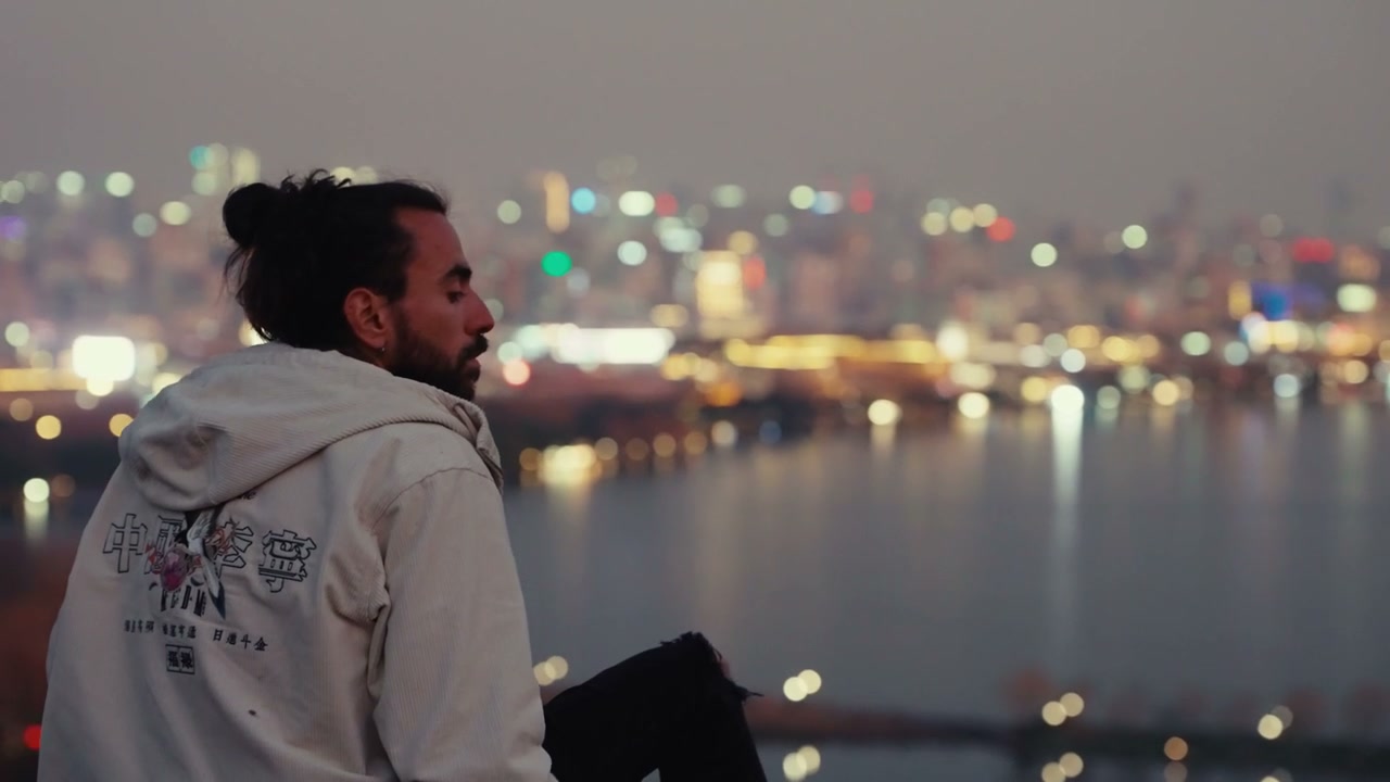 Man Sitting Overlooking Hangzhou Cityscape at Dusk