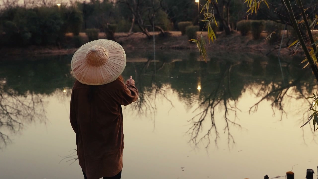 Person in Conical Hat Throws Stones in Lake