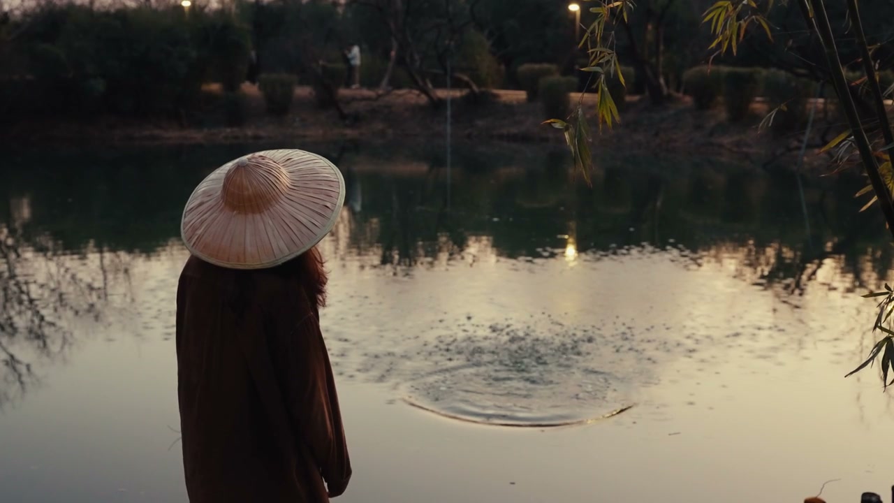 Person in Conical Hat Throws Stone in Pond