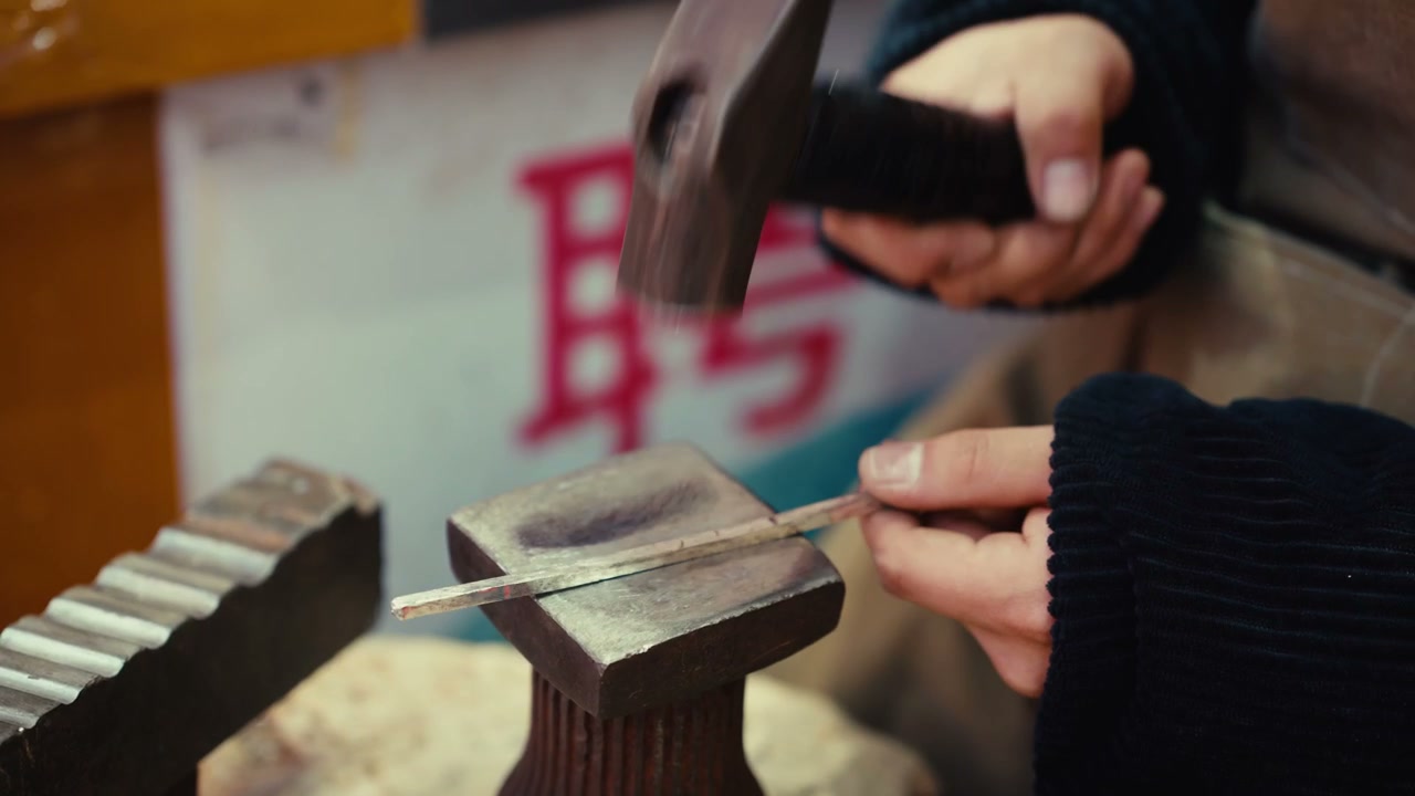 Craftsperson Hammering Metal Bar on Anvil