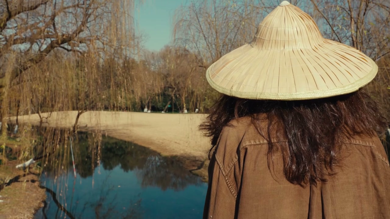 Person in Straw Hat Looking at Pond