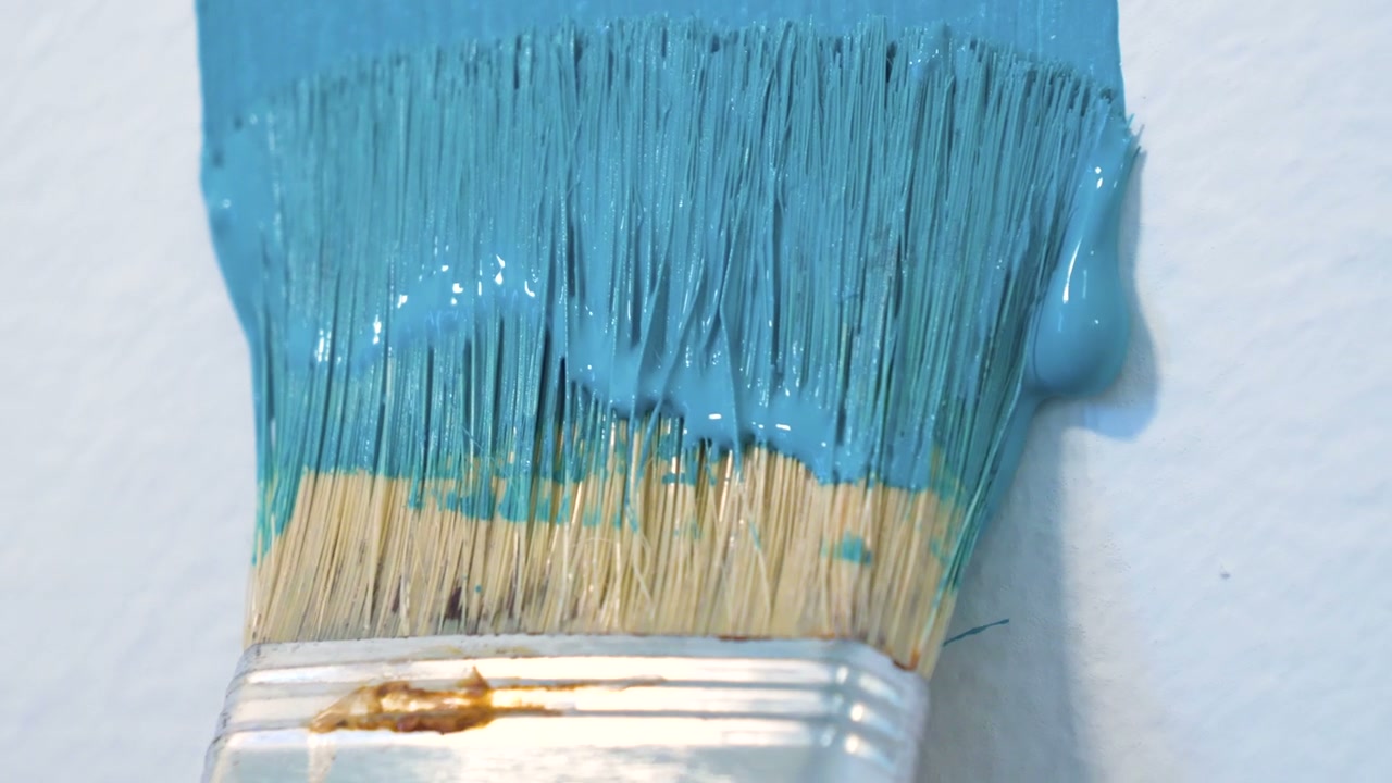 Paint Brush Applying Blue Paint to Wall