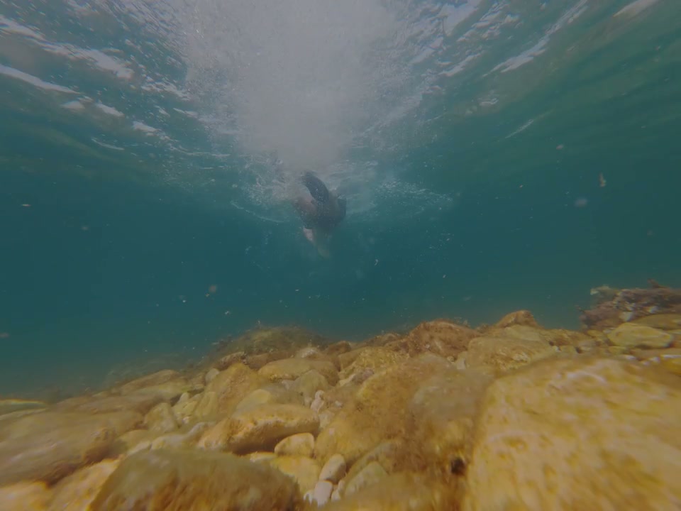 Person Swimming Over Rocks Underwater