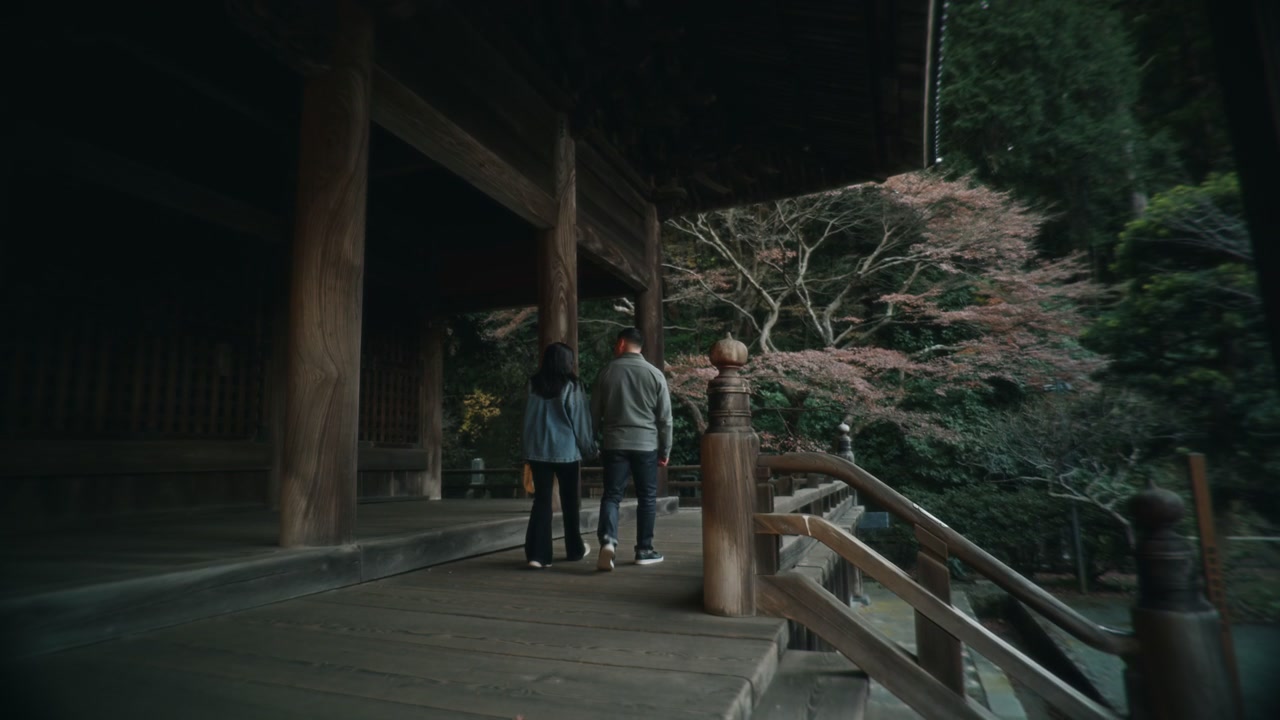 Two People Walk on Traditional Temple Veranda