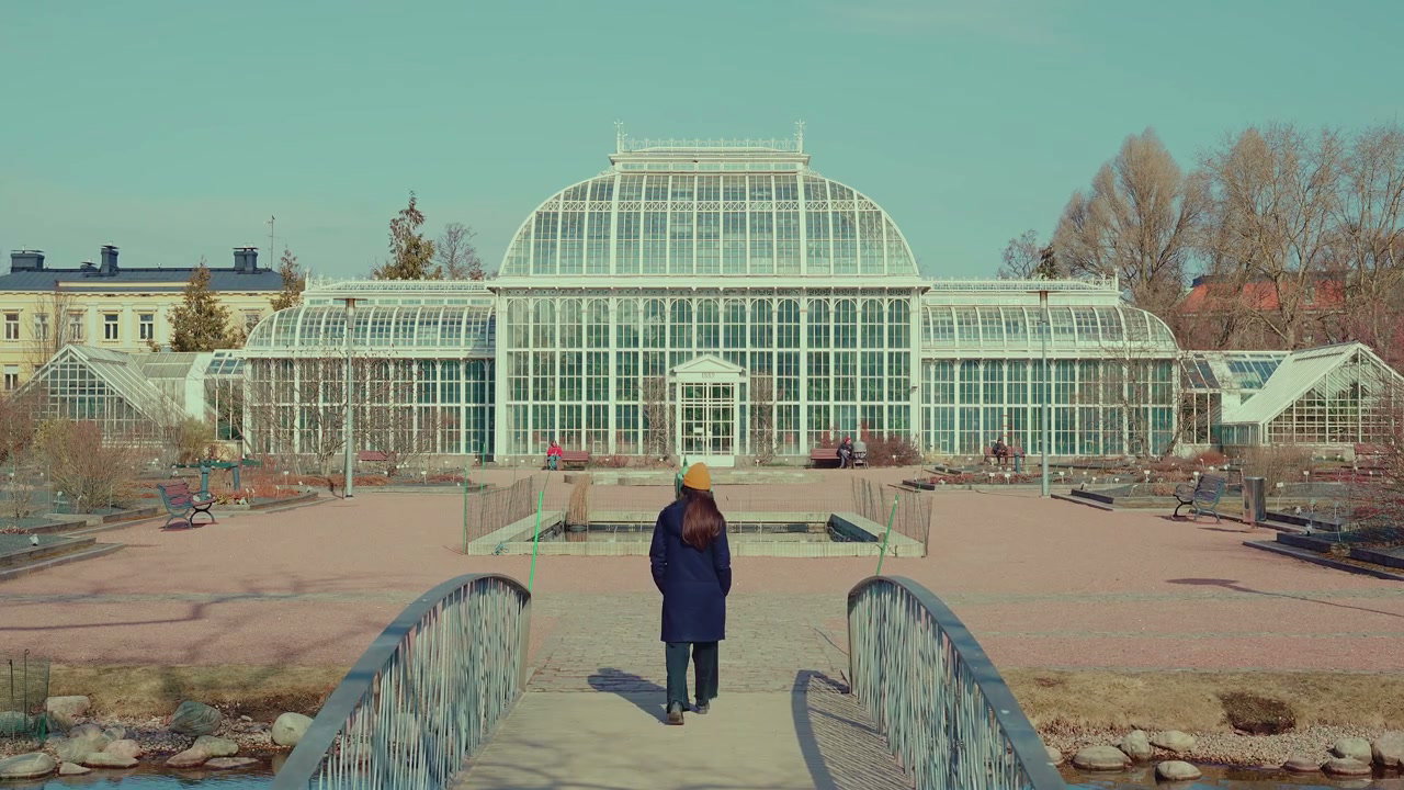 Person Walking Towards Ornate Greenhouse