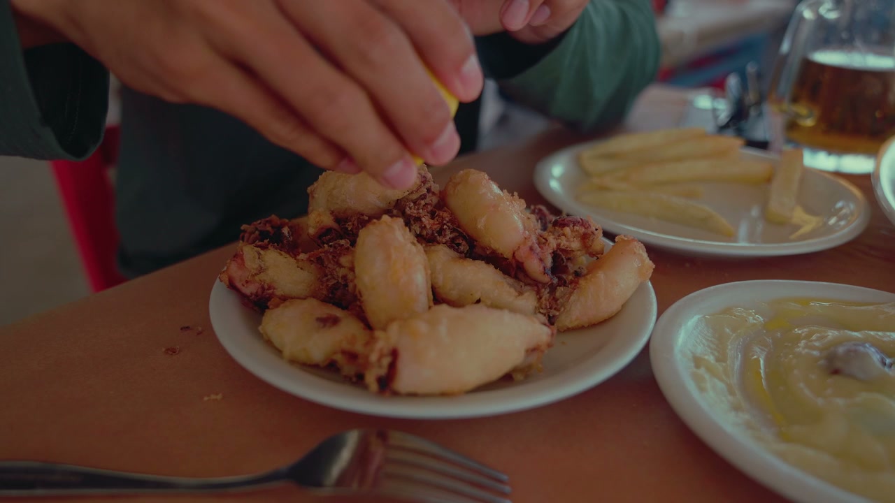 Person Squeezing Lemon On Fried Calamari