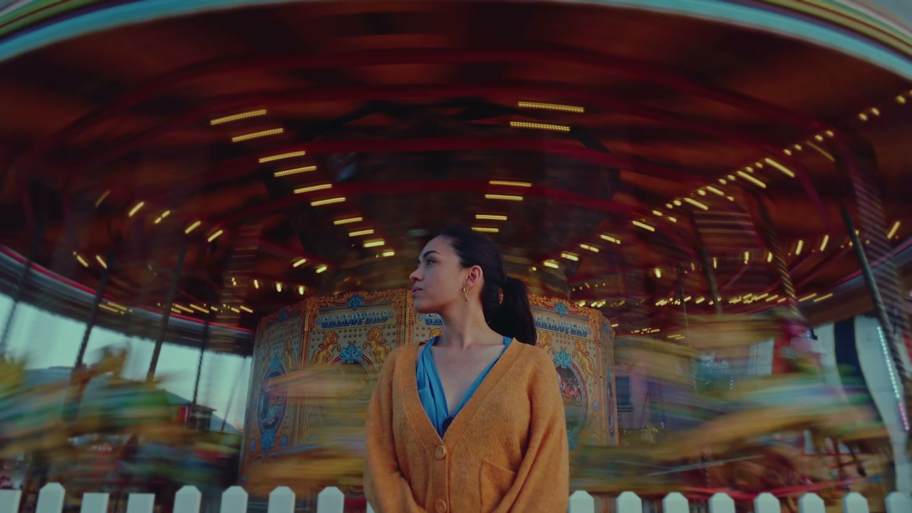 Woman Standing Before Spinning Carousel at Pier