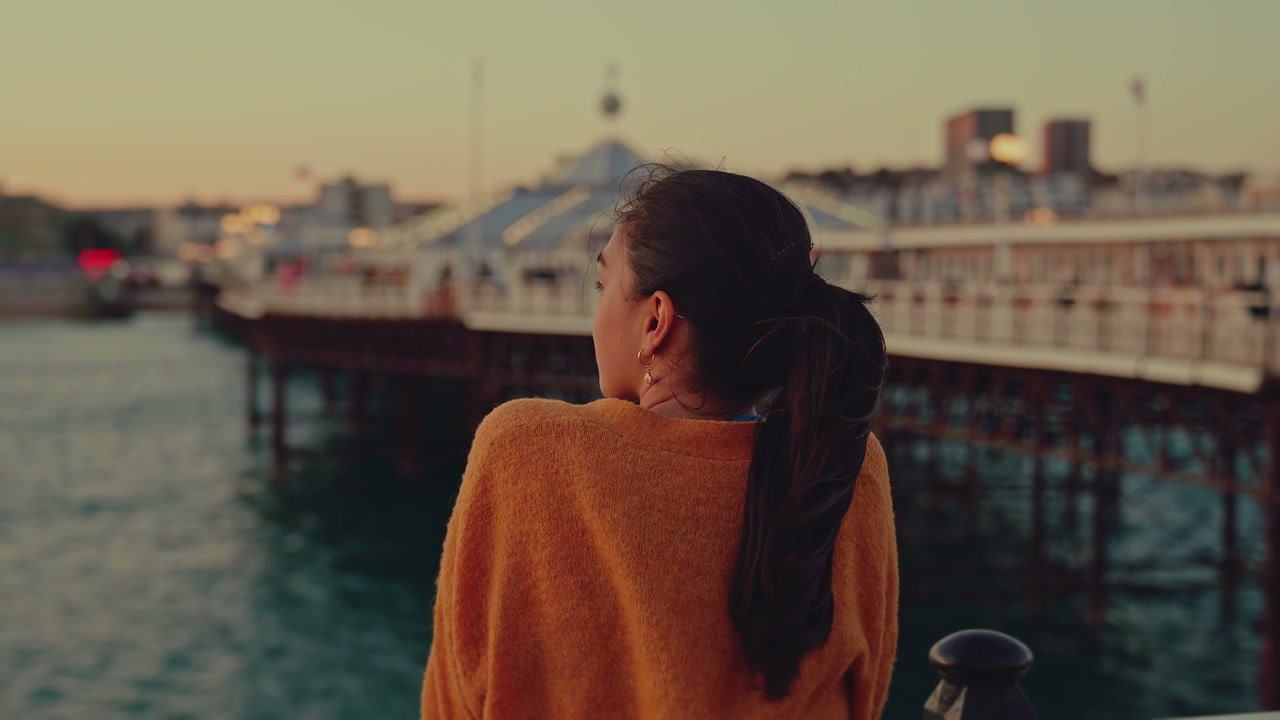 Woman Looking Out from Brighton Pier at Sunset