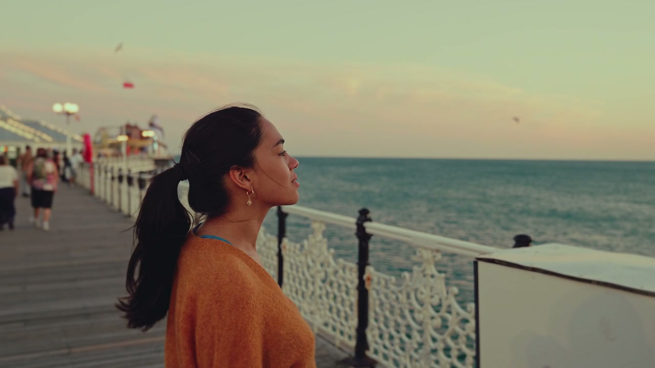 Young Woman Looking Up on Brighton Pier at Sunset