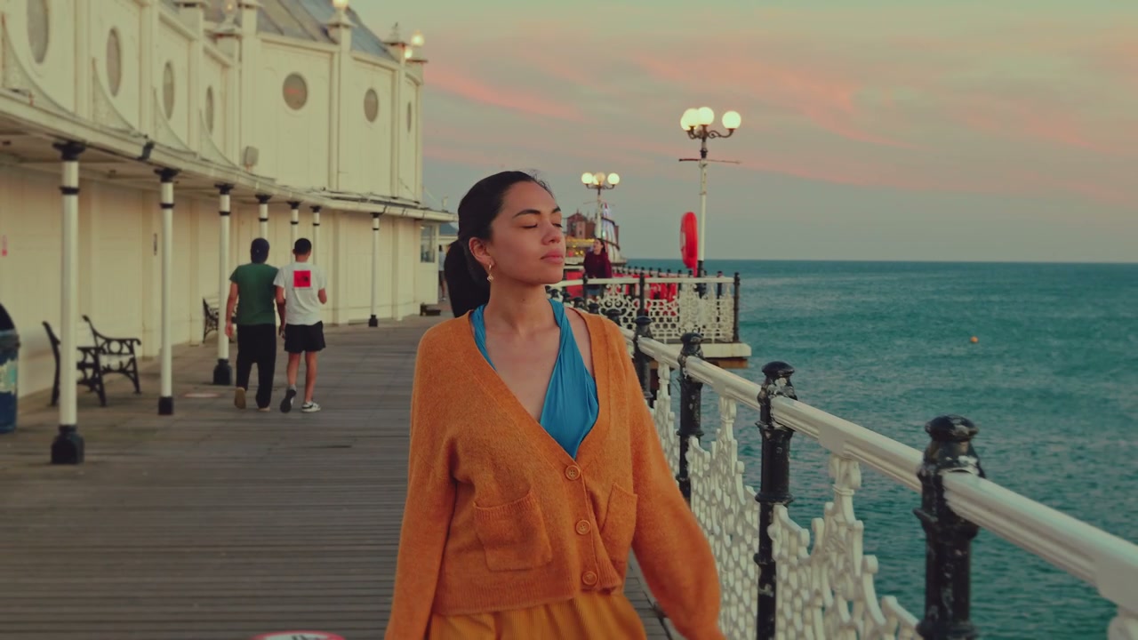 Young Woman Walking on Brighton Pier at Sunset