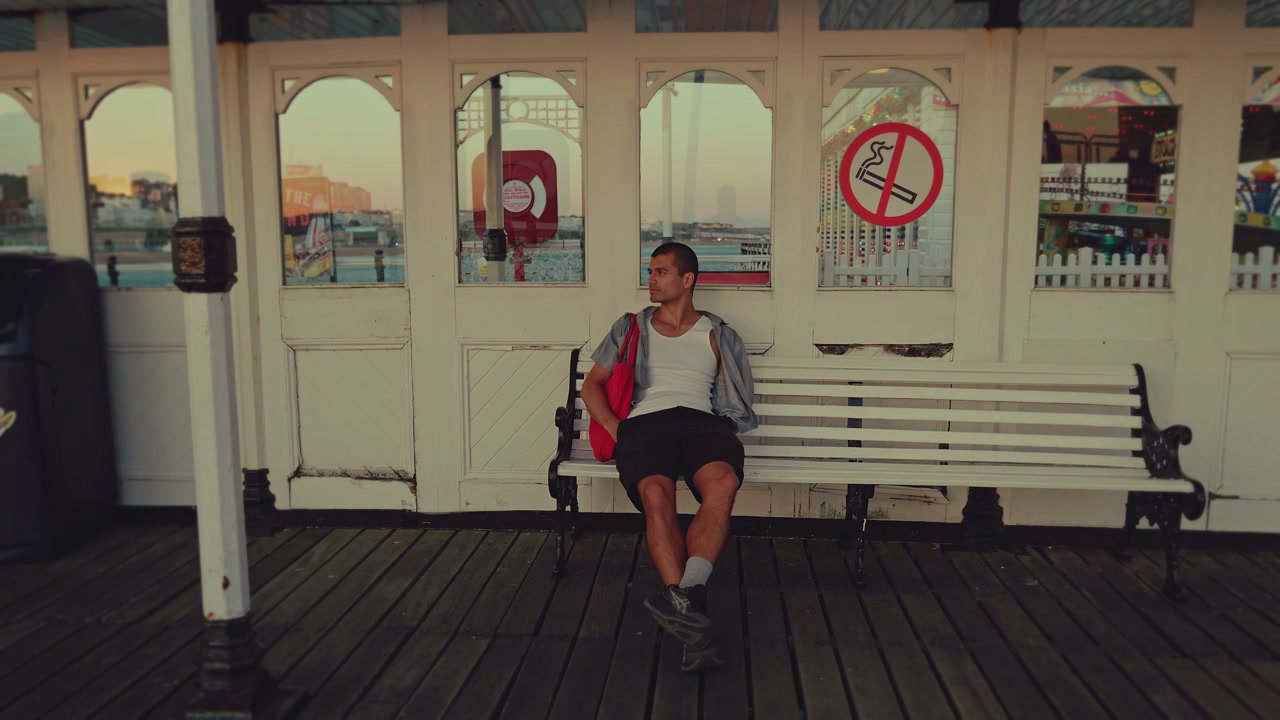 Young Man Sitting on Bench at Brighton Pier