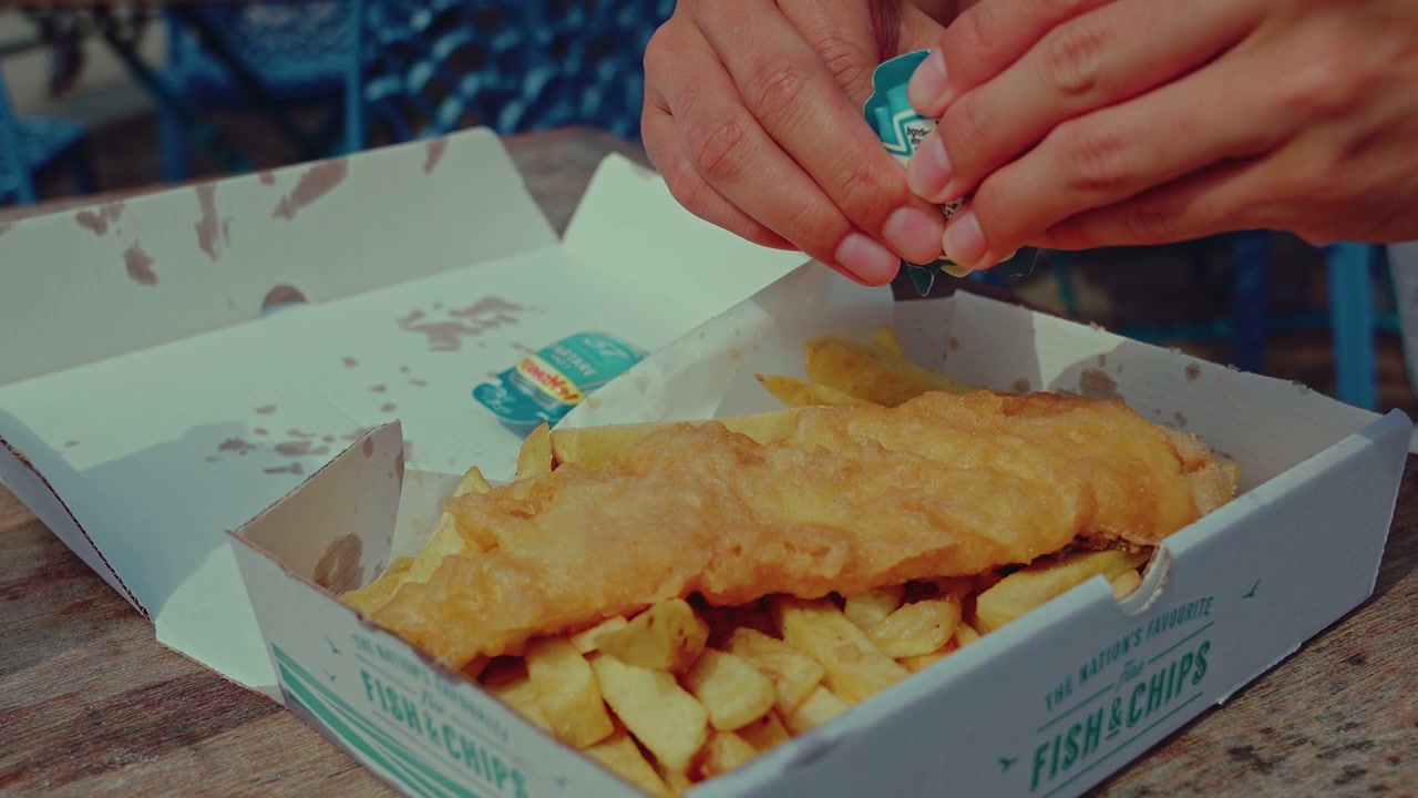 Hands Adding Tartar Sauce to Fish and Chips