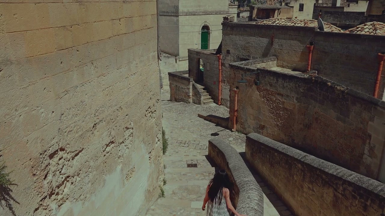 Woman Walks Down Stone Alley in Matera, Italy