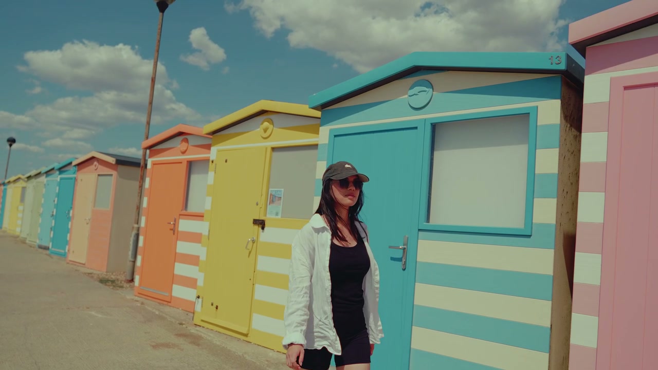 Woman Walking by Colorful Striped Beach Huts