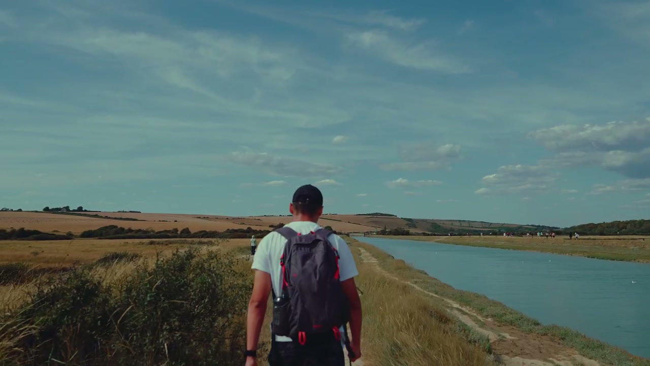 Man Hiking Riverside Path on Sunny Day