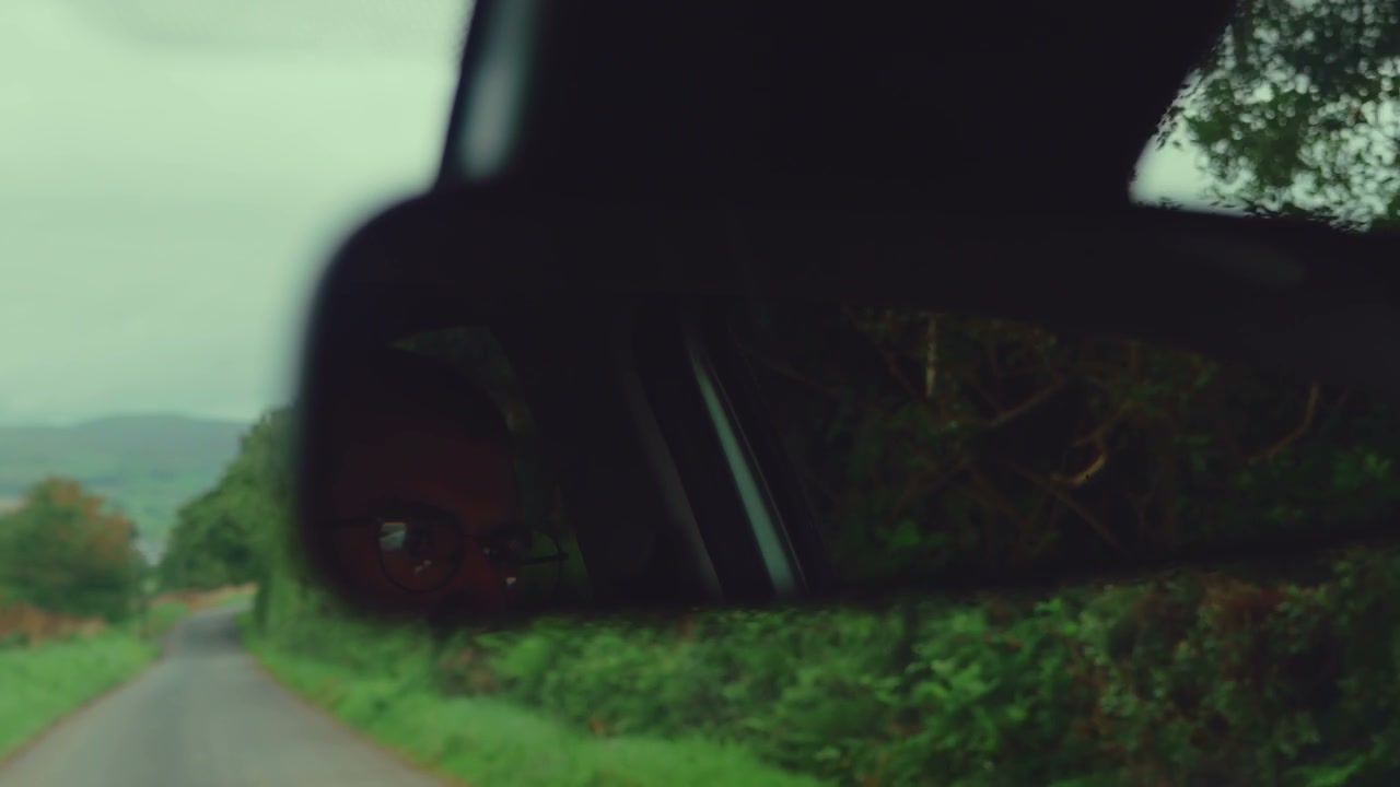 Driver's Reflection and Road in Car Mirror