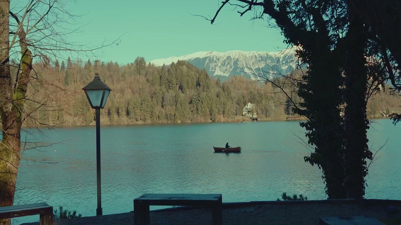 Person Rowing Boat on Lake Bled with Mountains