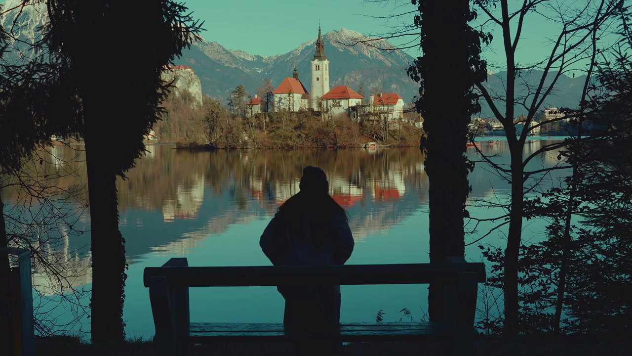 Person Sits on Bench Looking at Lake Bled Island