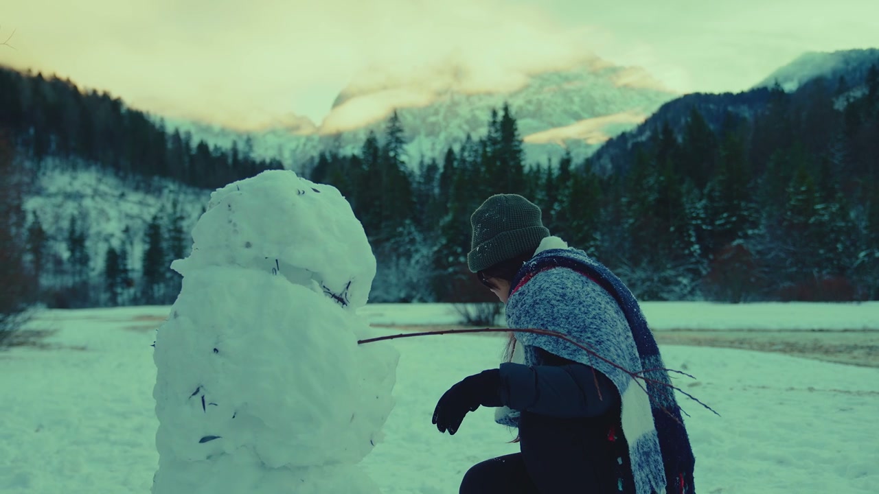 Woman Building Snowman in Winter Mountains